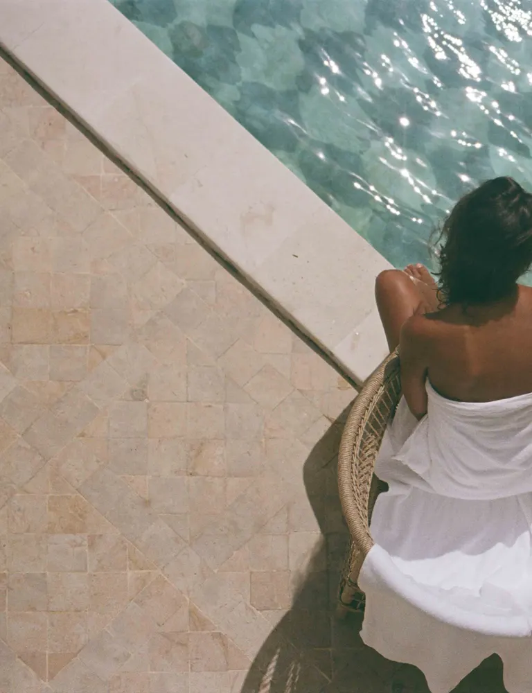 Bather beside a sunlit pool, seen from above